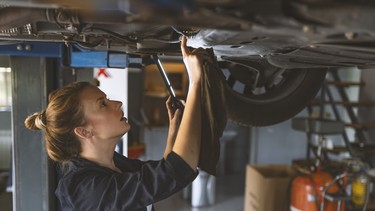 An attractive woman mechanic working on a car in a repair shop