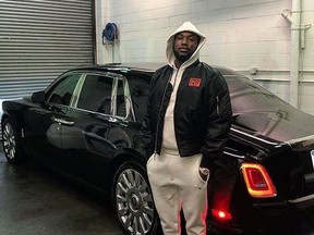 Rapper Meek Mill standing next to his black 2018 Rolls-Royce Phantom