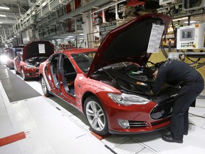 In this May 14, 2015, file photo, Tesla employees work on a Model S cars in the Tesla factory in Fremont, California.