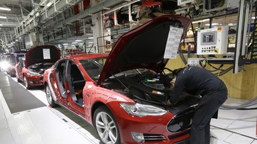 In this May 14, 2015, file photo, Tesla employees work on a Model S cars in the Tesla factory in Fremont, California.