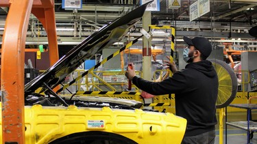 A worker in FCA's Brampton Assembly facility works around a shield meant to protect from coronavirus.