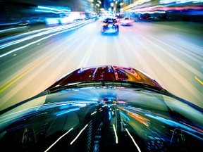 A car speeding at night, causing motion blur.