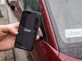 The Uber app is seen on an iPhone near a driver's vehicle after the company launched service, in Vancouver, Friday, Jan. 24, 2020.