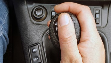 A hand holding a stickshift in a manual transmission car