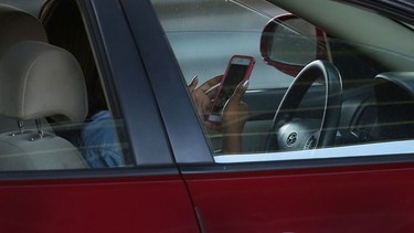 A driver uses a phone while behind the wheel of a car on April 30, 2016 in New York City.