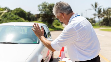 senior instructor teaching learner driver to park a car in testing ground