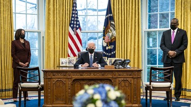 Flanked by Vice President Kamala Harris (L) and Secretary of Defense Lloyd Austin (R), U.S. President Joe Biden signs an executive order in the Oval Office of the White House on January 25, 2021 in Washington, DC.