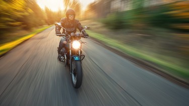 A motorcycle rider speeding through a forest.