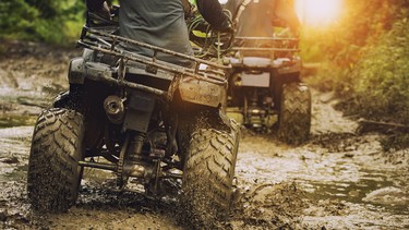 A man riding an ATV off-road through mud