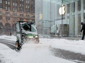 Workers clear a street outside the Apple Fifth Avenue during a snow storm, amid the coronavirus disease (COVID-19) outbreak, in the Manhattan borough of New York City, New York, U.S., February 1, 2021.