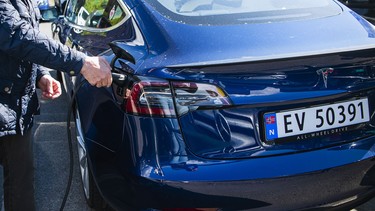 Un homme charge sa voiture électrique Tesla Motors sur un parking pour voitures électriques à Oslo, le 3 mai 2019.