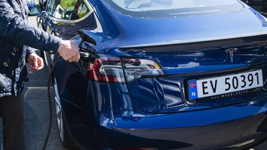 A man charges his Tesla Motors electric car at an all-electric cars parking lot in Oslo on May 3, 2019.