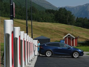 A driver prepares to charge his Tesla car at a Tesla Supercharger charging station on August 12, 2020 in Skei, Norway.