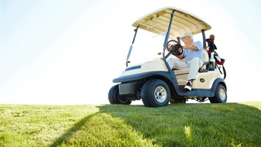 A senior retired couple driving a golf cart on a golf course