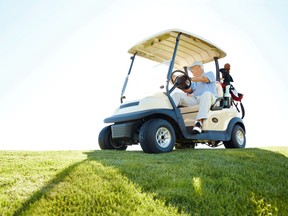 A senior retired couple driving a golf cart on a golf course