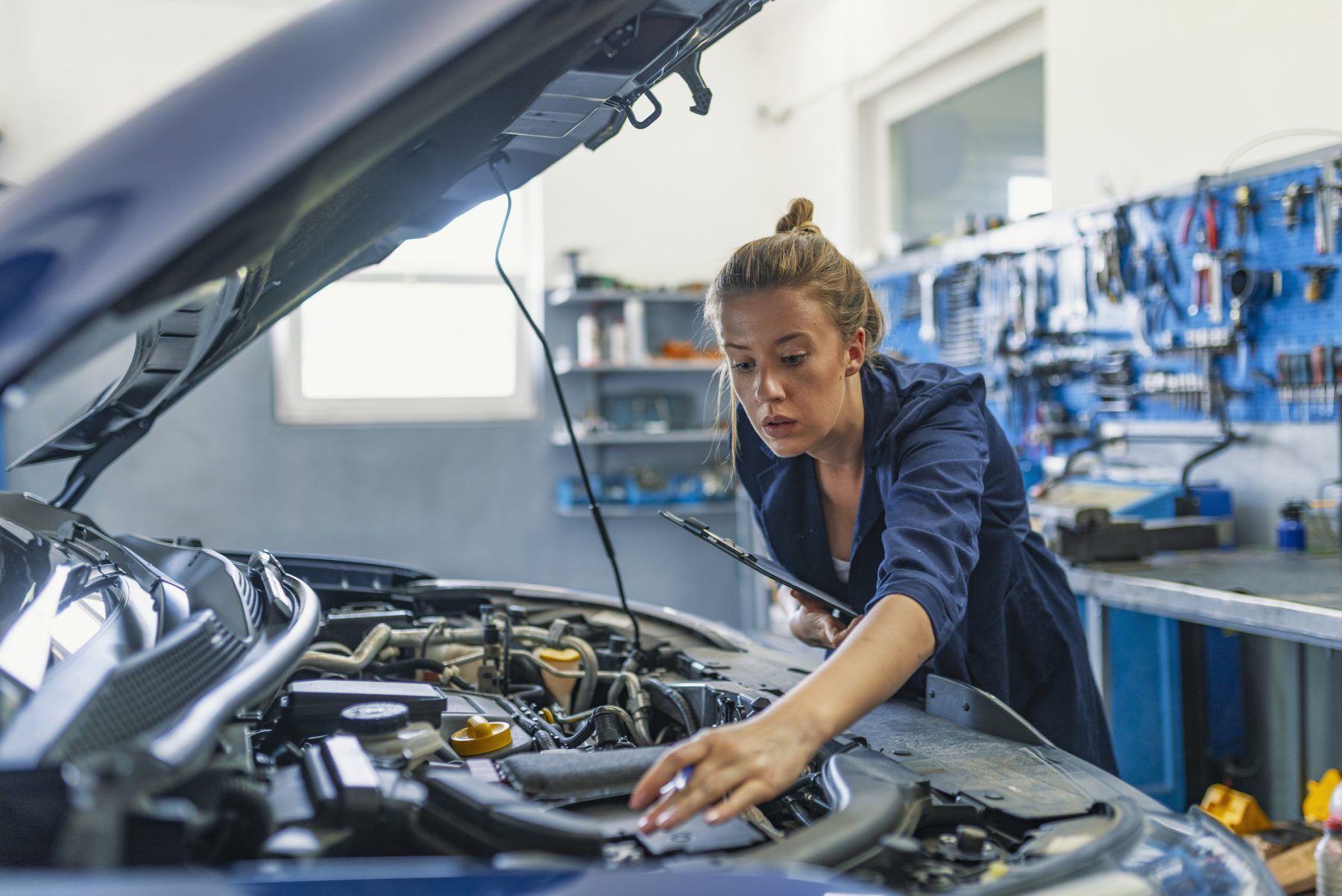 Portrait of a happy mechanic woman working on a car in an auto repair shop. Female mechanic working on car