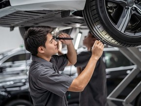 mechanic Checking and torch tire in maintainance service center which is a part of showroom, technician or engineer professional work for customer, car repair concept