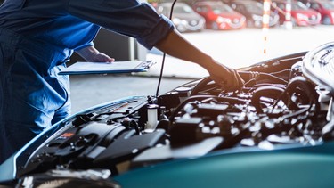 Car mechanic holding clipboard and checking to maintenance vehicle by customer claim order in auto repair shop garage. Engine repair service. People occupation and business job. Automobile technician