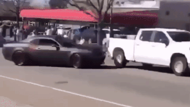 A Dodge Challenger Hellcat flipping a Chevrolet truck near a car meet in Colorado