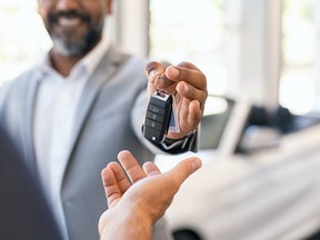 A car dealer handing over the keys to a new convertible.