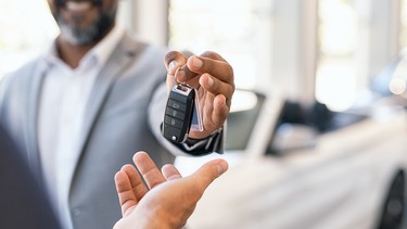 A car dealer handing over the keys to a new convertible.