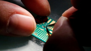 A researcher plants a semiconductor on an interface board during a research work to design and develop a semiconductor product at Tsinghua Unigroup research centre in Beijing, China, February 29, 2016.