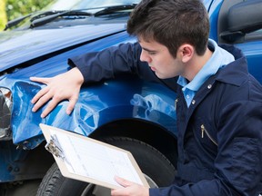 Auto Workshop Mechanic Inspecting Car And Filling In Repair Estimate