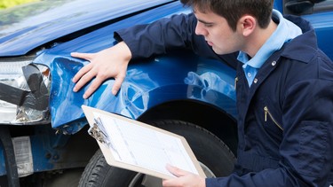 Auto Workshop Mechanic Inspecting Car And Filling In Repair Estimate