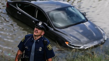 A Michigan State police officer investigates a car that is believe to have driven into the water on I-94 near the Livernois Avenue exit in Detroit on Monday, June 28, 2021.