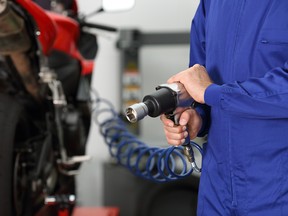 Close up of a motorcycle mechanic hand holding a pneumatic gun in a mechanical workshop