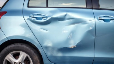 Close up of a blue car door that's been damaged.