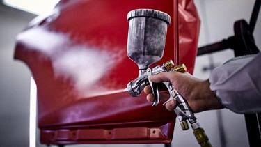 Painting a car door red in a painting chamber.