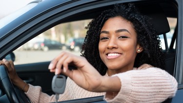 Happy young black woman seated in her new car