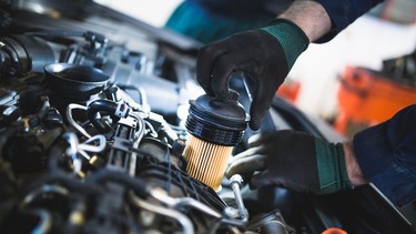 Close up hands of unrecognizable mechanic doing car service and maintenance. Oil and fuel filter changing.