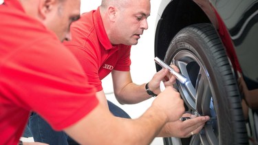 Audi service technicians looking at a rim during a training exercise.