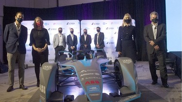 Dignitaries and officials gather around a race car after the announcement of the Canadian E-Fest program at the Douglas Hotel in Vancouver on Sept. 29, 2021.