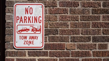 A 'No Parking' sign on a brick wall.