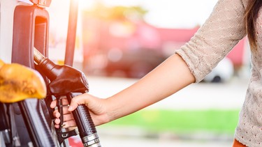 A woman grabbing a gas station fuel nozzle