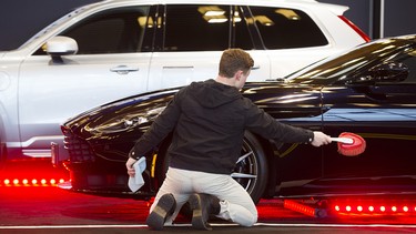 Oliver Auer dusts an Aston Martin DB11 on display at a previous Vancouver International Auto Show at the Vancouver Convention Centre
