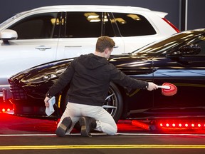 Oliver Auer dusts an Aston Martin DB11 on display at a previous Vancouver International Auto Show at the Vancouver Convention Centre.