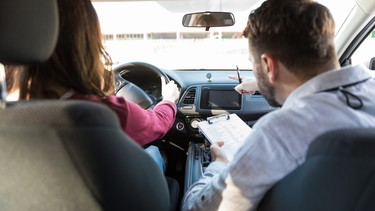 Rear view of a driving instructor pointing to a parking spot