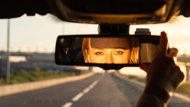 A driver adjusting the rearview mirror of her car