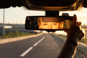 A driver adjusting the rearview mirror of her car