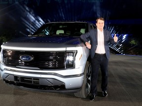 Ford CEO Jim Farley poses with the all-electric Ford F-150 Lightning pickup truck during the unveiling at the company's world headquarters in Dearborn, Michigan, U.S., May 19, 2021.