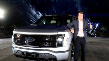 Ford CEO Jim Farley poses with the all-electric Ford F-150 Lightning pickup truck during the unveiling at the company's world headquarters in Dearborn, Michigan, U.S., May 19, 2021.