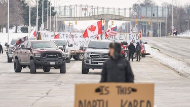 Anti vaccine mandate protestors block the roadway leaving the Ambassador Bridge border crossing, in Windsor, Ontario on Tuesday.