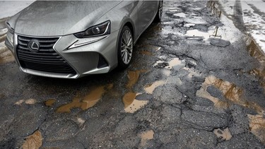 A car passes over a pothole-filled section of asphalt on 44th Ave. in the Lachine borough of Montreal on Monday March 7, 2022.
