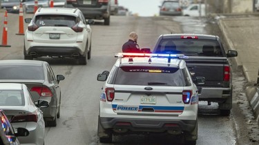 Cpl. Jason Wilkinson stands in front of a police vehicle equipped with an Automated Licence Plate Reader after pulling over a vehicle on Winnipeg Street in Regina on March 31, 2022.