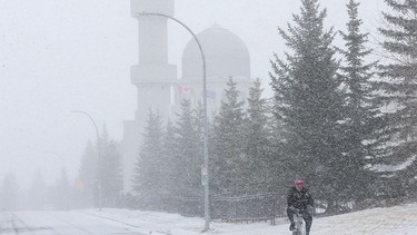 FILE - The Baitun-Nur Mosque is obscured by a sudden spring snow storm as a man braves the storm cycling along 54th Avenue N.E. in Calgary on Wednesday, April 13, 2022.