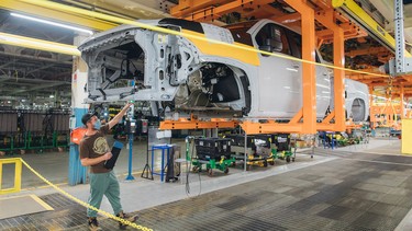 A separated truck cab and bed move through an assembly line at General Motors' Oshawa assembly plant as employees work below